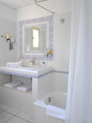a white bathroom with a sink and a mirror at Hotel Spa Le Calendal in Arles