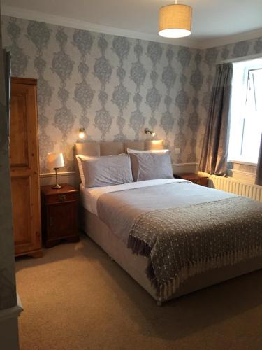 een slaapkamer met een bed, 2 lampen en een raam bij Albany Lodge in Portrush