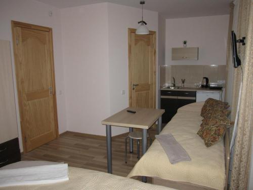 a room with two beds and a table and a kitchen at Vila Laima in Šventoji
