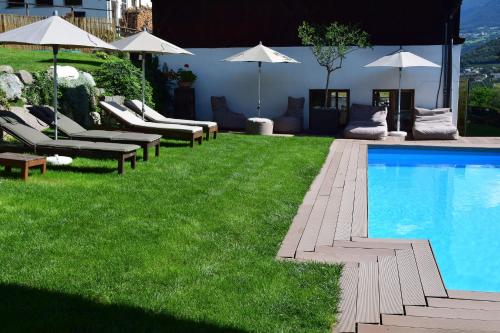 einen Pool mit Liegestühlen und Sonnenschirmen auf dem Rasen in der Unterkunft Pension Moarhof in Feldthurns