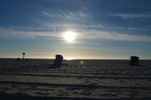 a beach with the sun setting on the horizon at Hotel Landhaus Ellerbrock in Sankt Peter-Ording