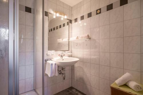a white bathroom with a sink and a shower at Hotel Enzian in Pertisau