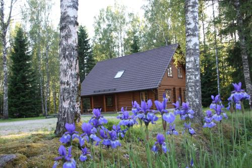 a log cabin with purple flowers in front of it at Aasa Holiday Homes in Kärsu