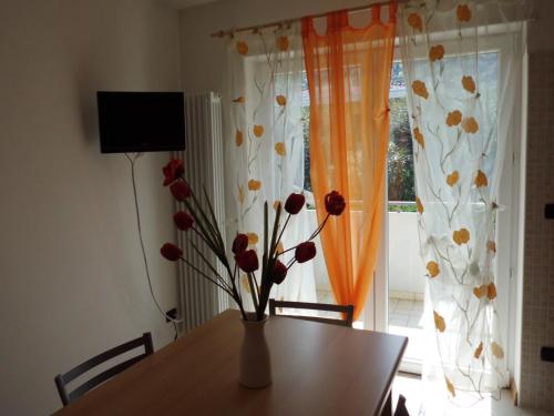 a vase with flowers on a table in front of a window at Agritur Laura in Nago-Torbole