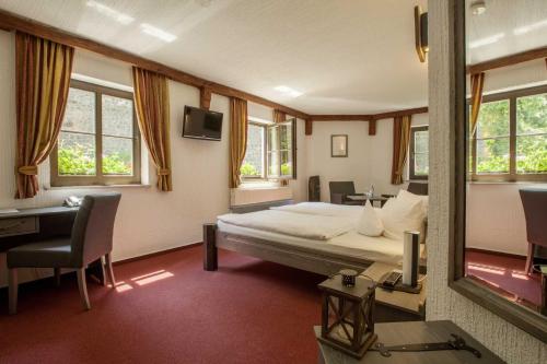 Schlafzimmer mit einem Bett, einem Schreibtisch und einem Spiegel in der Unterkunft Burghotel Stolpen in Stolpen