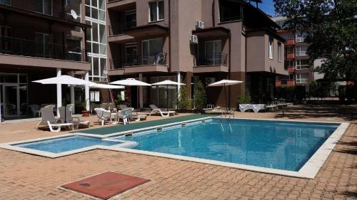 a patio area with a pool, chairs, and a lawn chair at St. Sofia Apartments - Official Rental in Sunny Beach