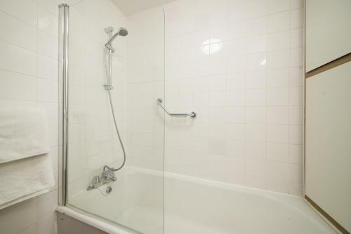 a shower with a glass door next to a tub at The Crown & Greyhound by Innkeeper's Collection in London