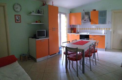 ヴァストにあるA pochi passi dal mareのキッチン(オレンジ色のキャビネット、テーブル、椅子付)