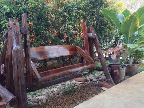 a wooden bench sitting in a garden with plants at Jim Guesthouse in Kanchanaburi
