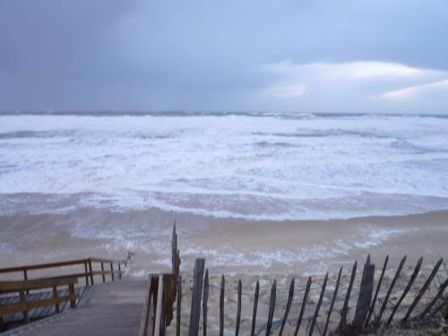 a view of the ocean from a beach with a fence at Chez Augustin in Lacanau-Océan