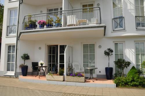 a white building with a balcony with potted plants at Ferienwohnung Anemone in Sassnitz