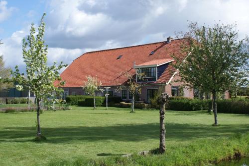 a house with a red roof and trees in the yard at Gastenverblijf De Natureluur in Noorden
