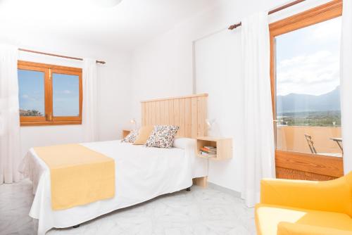 Habitación blanca con cama y ventana en Can Fusteret, en Son Serra de Marina