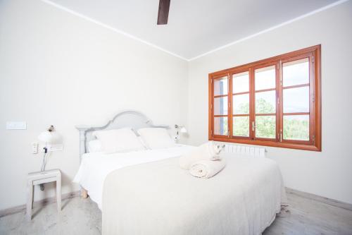 a white bedroom with a bed and a window at Finca Can Pol in Inca