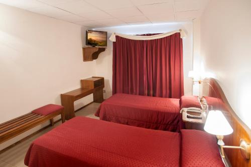 a room with two beds and a red curtain at Hotel Princess in Mendoza