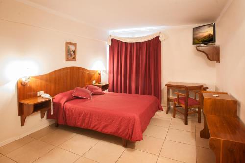 a hotel room with a red bed and a table at Hotel Princess in Mendoza