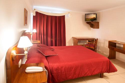 a hotel room with a red bed and a phone on a table at Hotel Princess in Mendoza