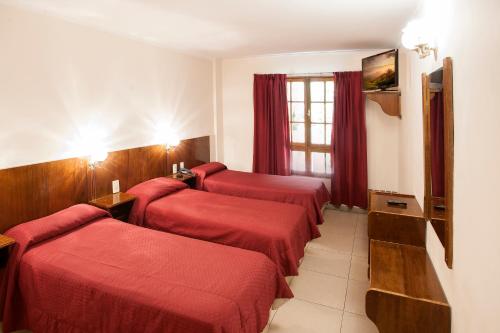 a hotel room with four red beds and a window at Hotel Princess in Mendoza