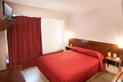 a bedroom with a red bed with a red blanket at Hotel Princess in Mendoza