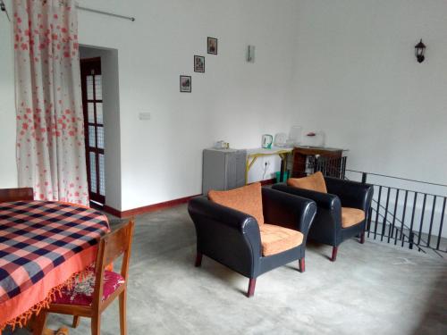 een woonkamer met 2 stoelen en een bed bij Chelli Homestay in Negombo