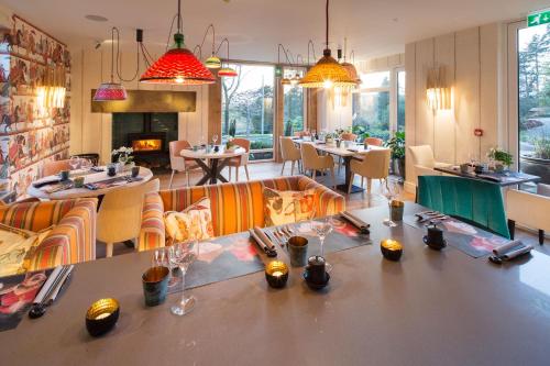 a restaurant with tables and chairs and a fireplace at Gilpin Hotel & Lake House in Bowness-on-Windermere