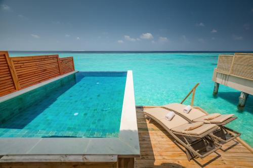 a swimming pool with chairs in the water at Kudafushi Resort & Spa in Raa Atoll