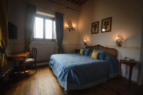 a bedroom with a bed with blue sheets and a window at Palazzo Pacini in Colle Val D'Elsa