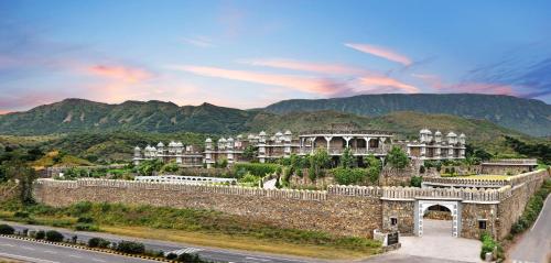 a building on a hill with mountains in the background at The Amargarh in Udaipur