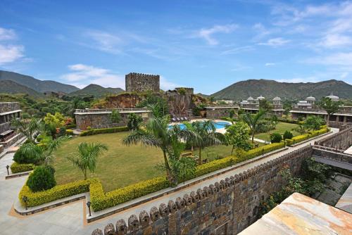 a resort with a pool and a castle in the background at The Amargarh in Udaipur