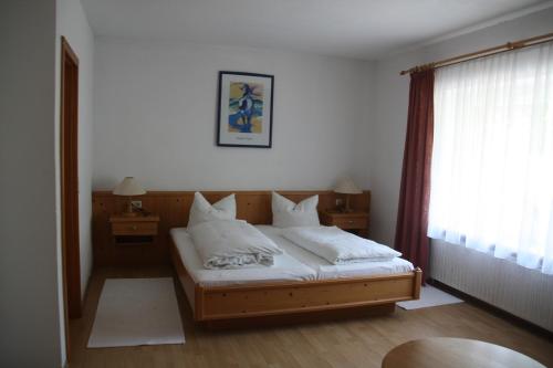 a bedroom with a bed with white sheets and a window at Pension Fuchsbau in Münchberg