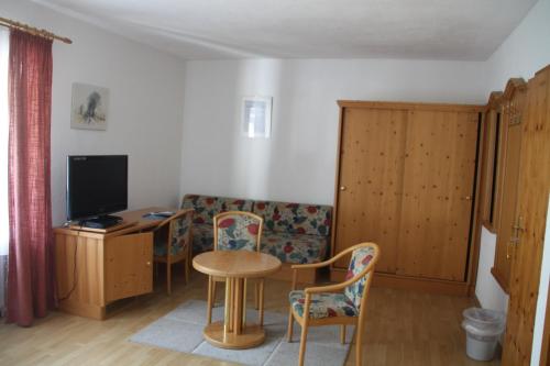 ein Wohnzimmer mit einem Tisch, Stühlen und einem TV in der Unterkunft Pension Fuchsbau in Münchberg