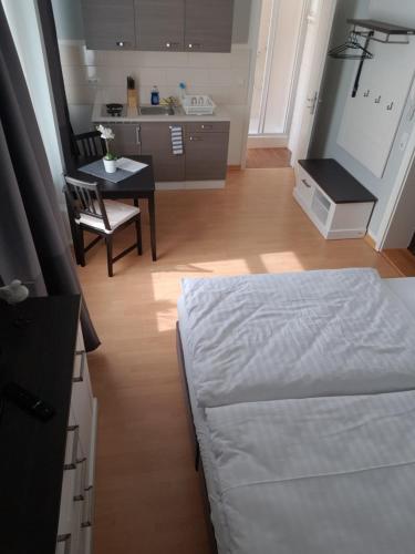 a bedroom with a bed and a table and a kitchen at Pension Fischerjung in Rostock