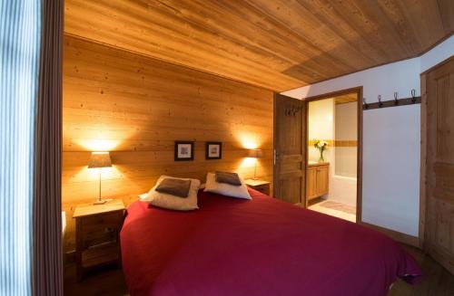 a bedroom with a red bed with a wooden wall at Chalet Belvedere by Chalet Chardons in Tignes