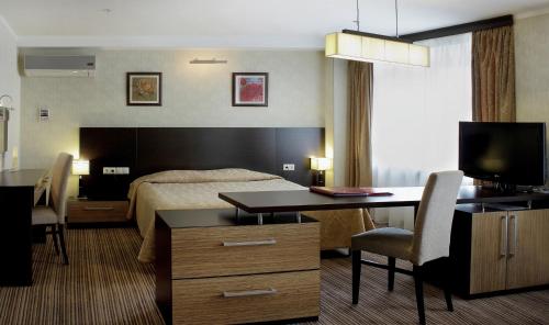 Habitación de hotel con cama y escritorio en Vega Hotel, en Tolyatti