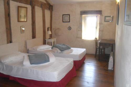 Habitación con 2 camas, mesa y ventana en Maison de Bastien, en Lugon et l’Ile du Carney