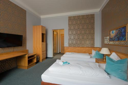 a hotel room with two beds and a flat screen tv at Hotel Ziegenkrug Schweriner Tor in Pampow
