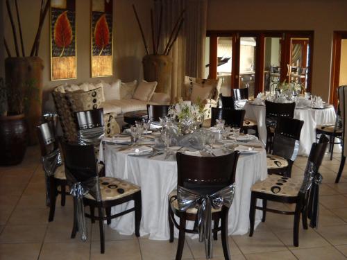 a dining room with white tables and chairs and a couch at Witwater Guest House & Spa in Kempton Park