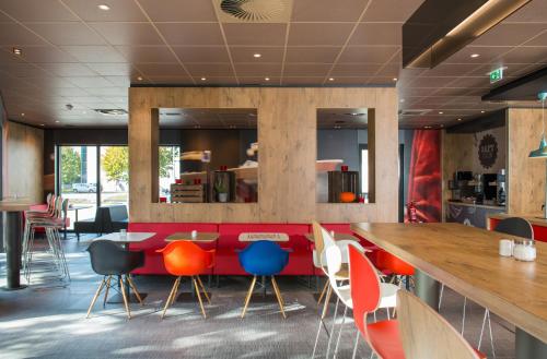 a bar in a restaurant with colorful chairs at Ibis München Airport Süd in Hallbergmoos