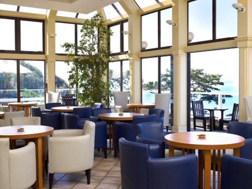 a restaurant with tables and chairs and windows at The Imperial Torquay in Torquay