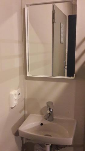 Hvammstangi Hostel في هفامستانغي: حمام مع حوض أبيض ومرآة