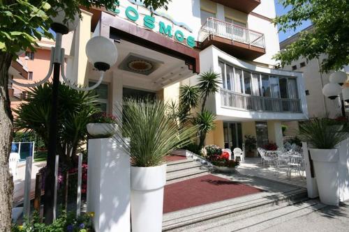 a large building with plants in front of it at Hotel Cosmos in Rimini
