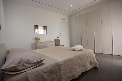 a white bedroom with a bed and a chair at House Etna View in Mascali