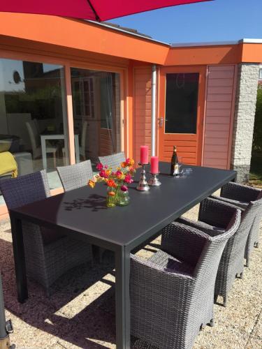 a black table with chairs and flowers on a patio at Ferienhaus am Meer mit Kamin & Sauna - Seestern 251 in Julianadorp