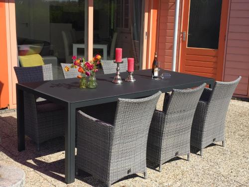 a black table and chairs with flowers and candles at Ferienhaus am Meer mit Kamin & Sauna - Seestern 251 in Julianadorp
