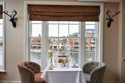 a table with chairs in front of a large window at Sir Christopher Wren Hotel in Windsor