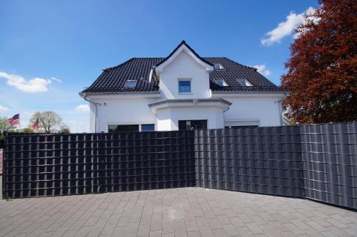 a white house behind a black fence at Pension / Zimmervermietung Wasbek in Wasbek