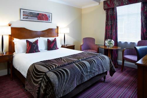 a hotel room with a bed and two chairs at Sir Christopher Wren Hotel in Windsor