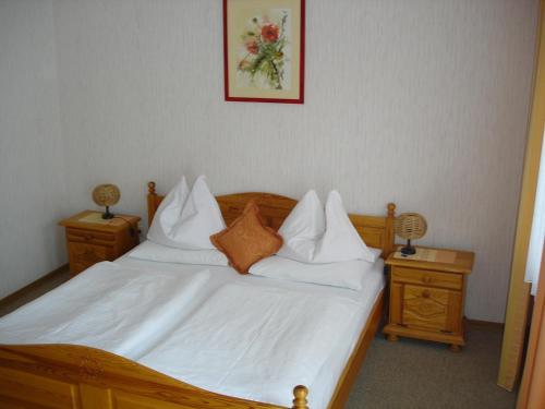een slaapkamer met een bed met witte lakens en kussens bij Weingut Pension Sommerhof in Mörbisch am See