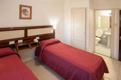a hotel room with two beds and a bathroom at Hotel Carollo in Mendoza