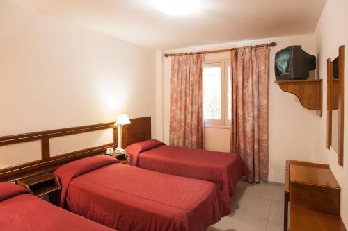 a hotel room with two beds and a tv at Hotel Carollo in Mendoza